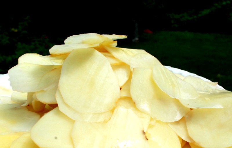 Sliced potatoes on cutting board. 