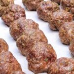 Baked venison meatballs on a parchment-lined baking sheet