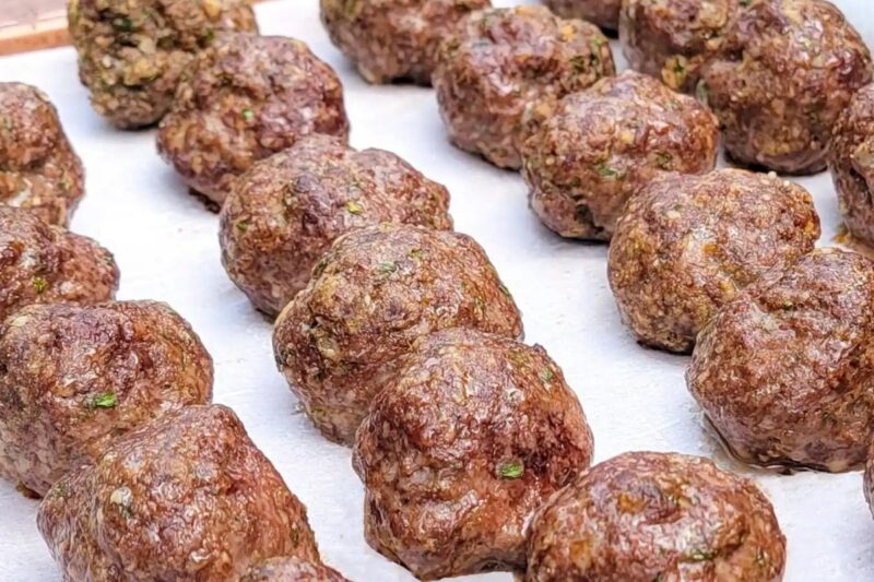 Baked venison meatballs on a parchment-lined baking sheet